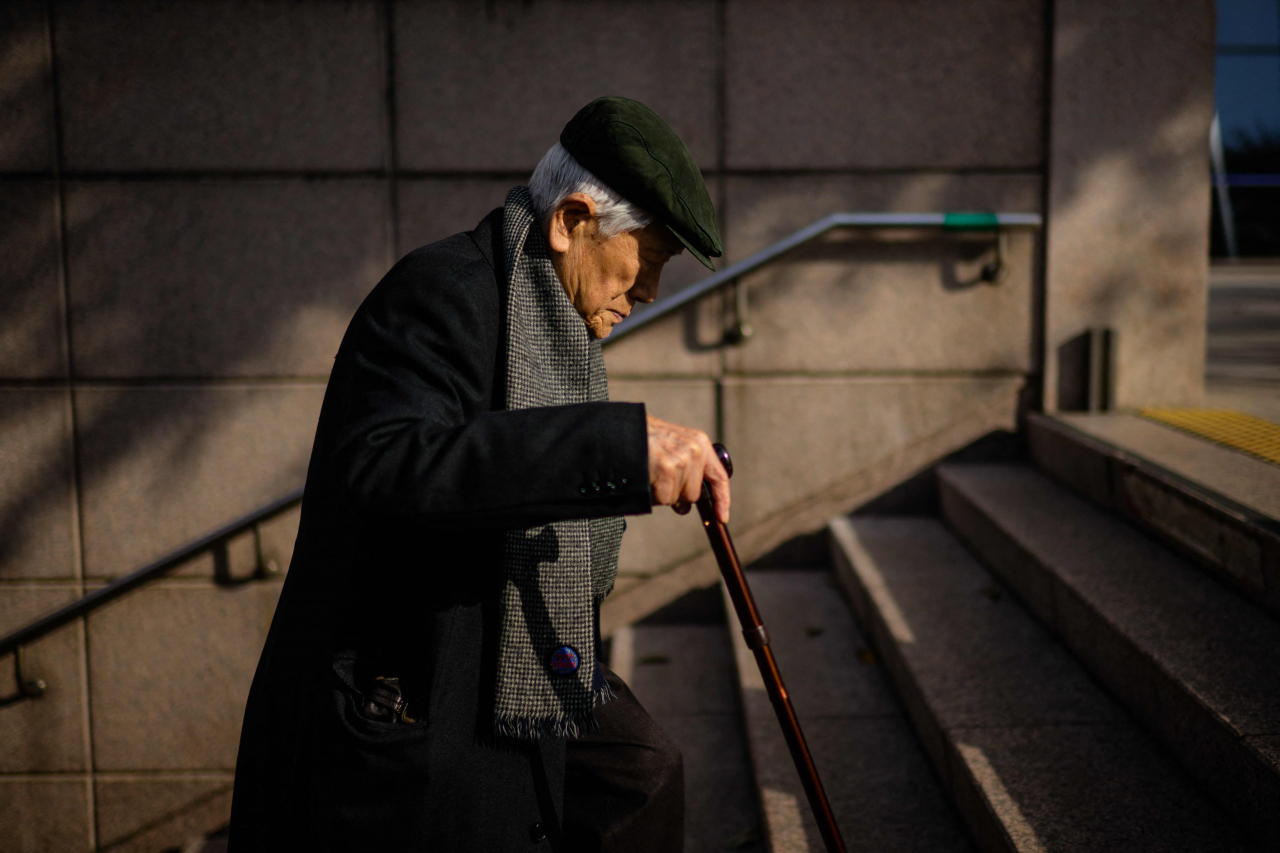 An aged man is seen climbing stairs at a subway station in Seoul, Nov. 22. (AFP-Yonhap)