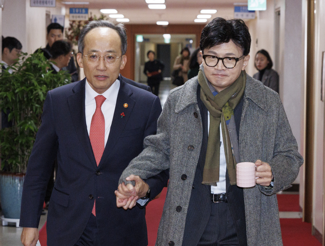 Deputy Prime Minister and Finance Minister Choo Kyung-ho (left) holds hands with Justice Minister Han Dong-hoon as they enter a Cabinet meeting at the Government Complex Seoul on Friday. (Yonhap)