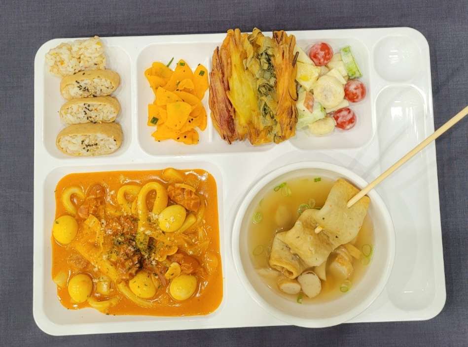 The menu of a school lunch is designed to cater to children’s preferences. The photographed meal showcases rose tteokbokki (bottom left), a popular snack made of gochujang blended with cream, and fishcake soup (bottom right). (Daegu Metropolitan Office of Education)”