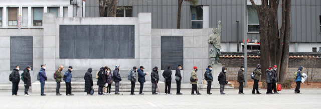 People wait in line at Tapgol Park in central Seoul to get lunch boxes as part of the city's free meal program. (The Korea Herald DB)