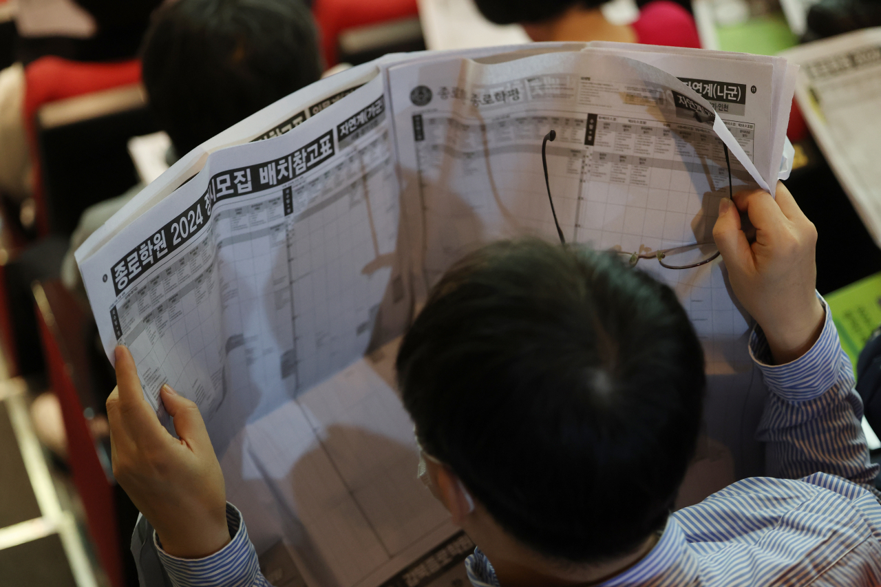 This photo is not directly related to the story. A parent of a student preparing for college admission reads the related information in this Dec.12 photo. (Yonhap)
