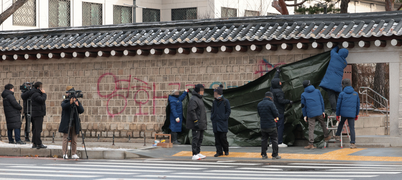 Officials are covering up the graffiti sprayed on the walls of Gyeongbok Palace in central Seoul on Saturday. (Yonhap)