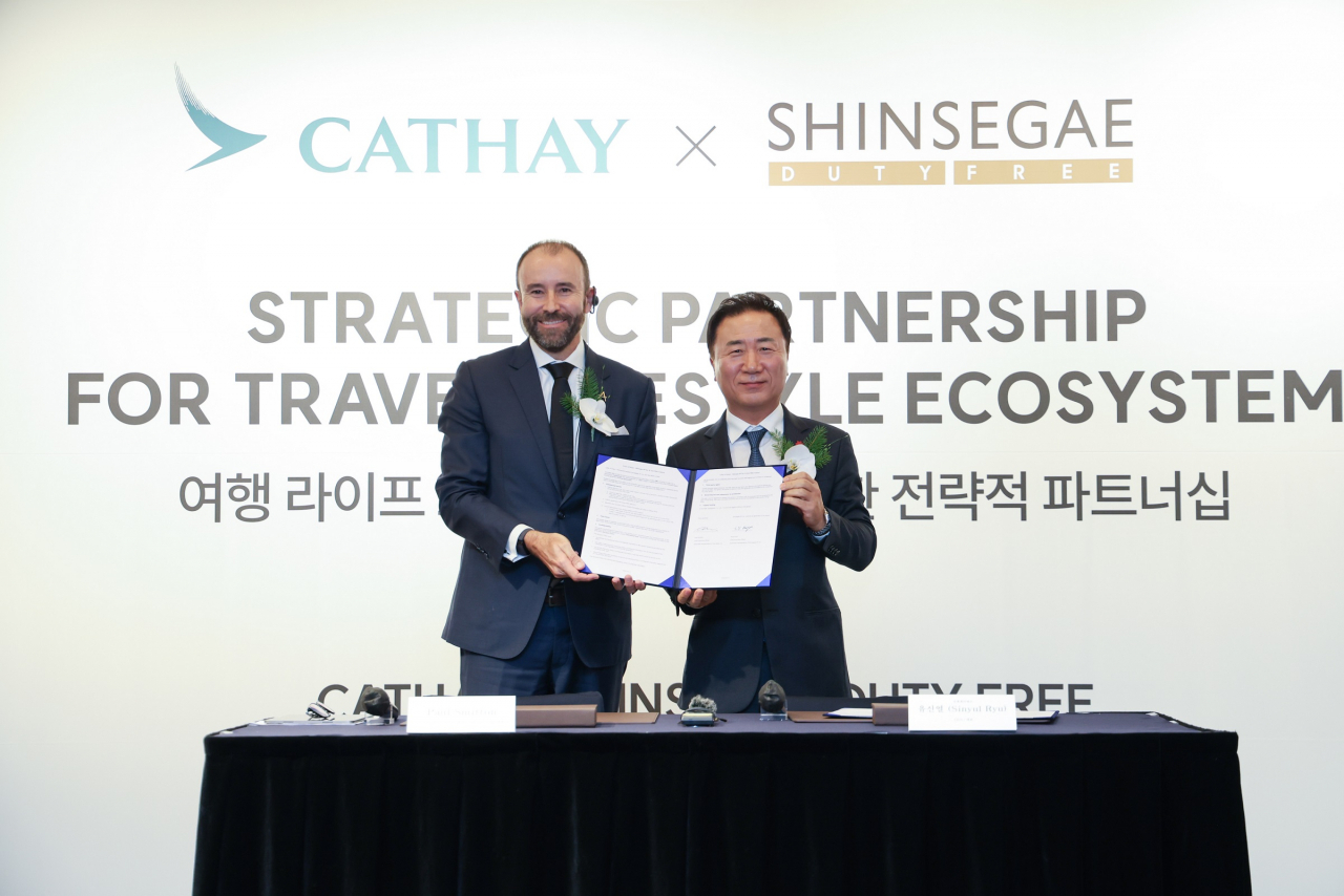 Ryu Sin-yul (right), CEO of Shinsegae Duty Free and Paul Smitton, CEO of Asia Miles Limited, pose for a photo upon signing a memorandum of understanding in Seoul, Tuesday. (Shinsegae DF)