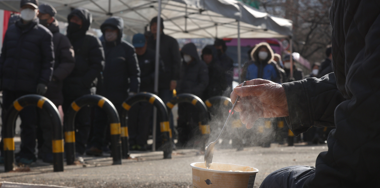 People line up in the cold for free meals at a park in Daegu on Tuesday. (Yonhap)