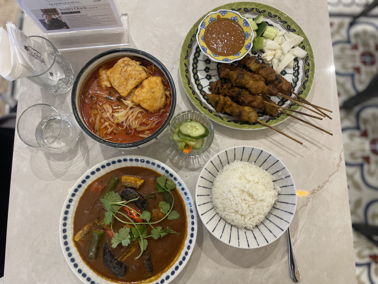 Clockwise from left: Singapore laksa, Singapore satay and house made peanut sauce, Singapore fish curry and rice. (Kim Da-sol/The Korea Herald)