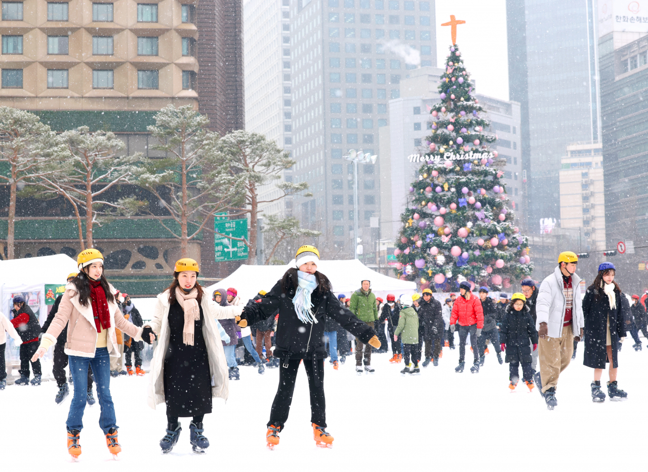 People skate on an outdoor rink set up at Seoul Plaza in downtown Seoul on Monday as they enjoy a white Christmas. (Yonhap)