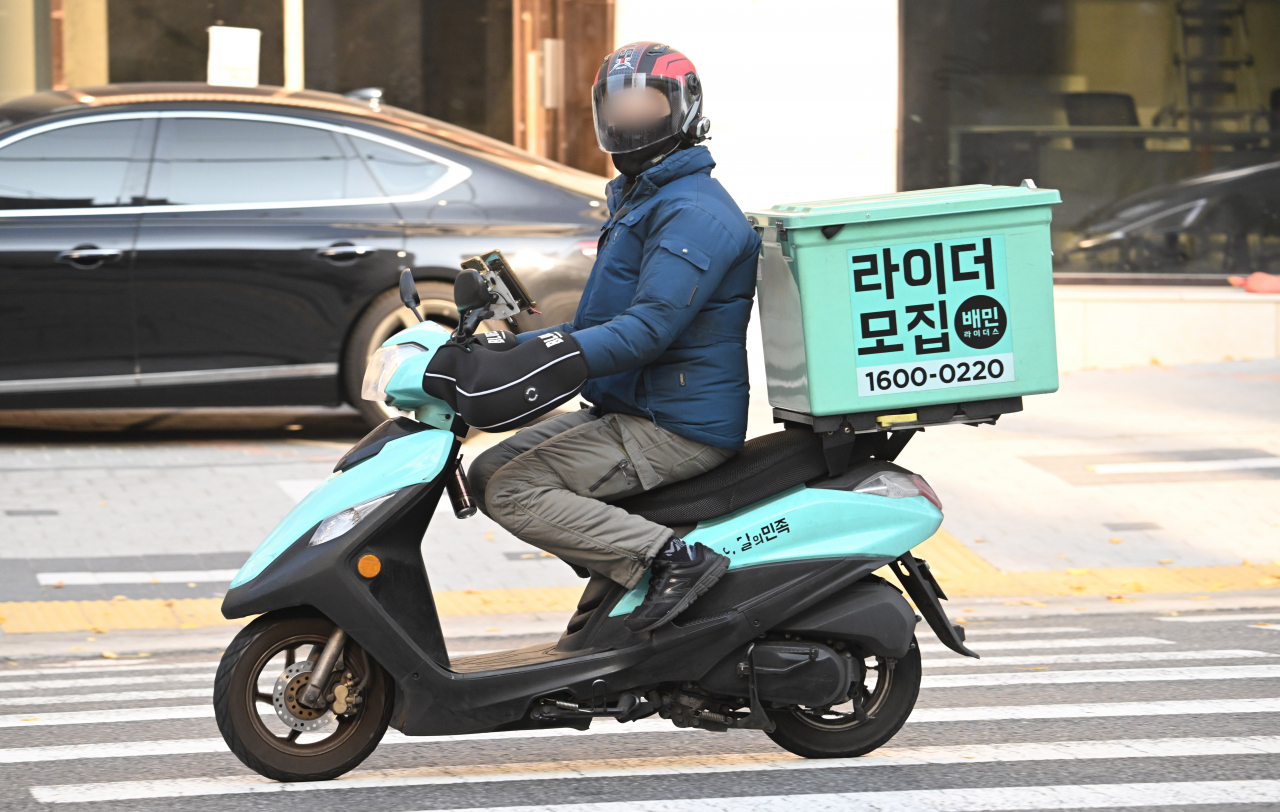 A Baemin delivery worker waits at a traffic light. (Im Se-jun/The Korea Herald)