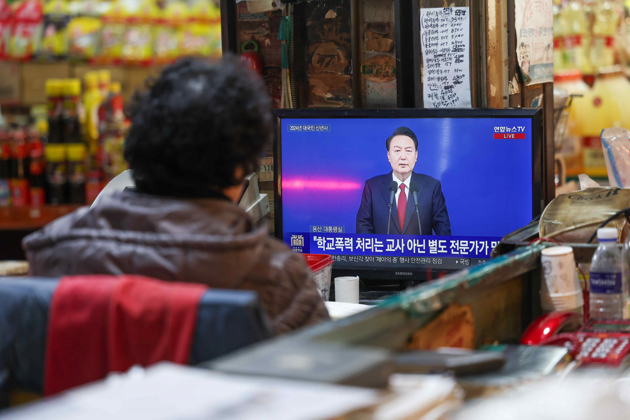 A shop owner in Seoul watches a televised speech by President Yoon Suk Yeol on Monday. (Yonhap)