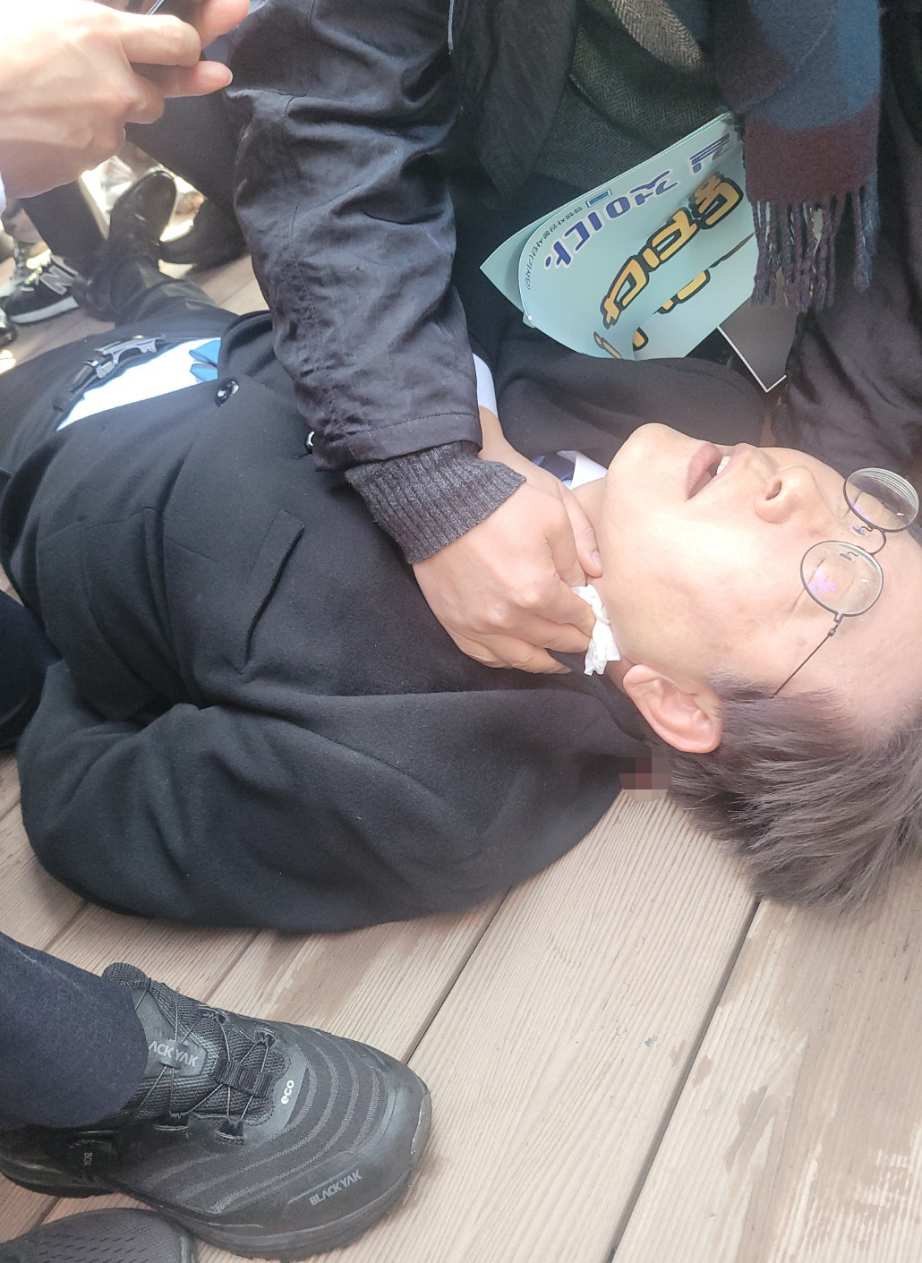 Lee Jae-myung, the leader of the main opposition Democratic Party, lies on the floor after he was attacked Tuesday by an unidentified individual during his visit to Busan. (Yonhap)