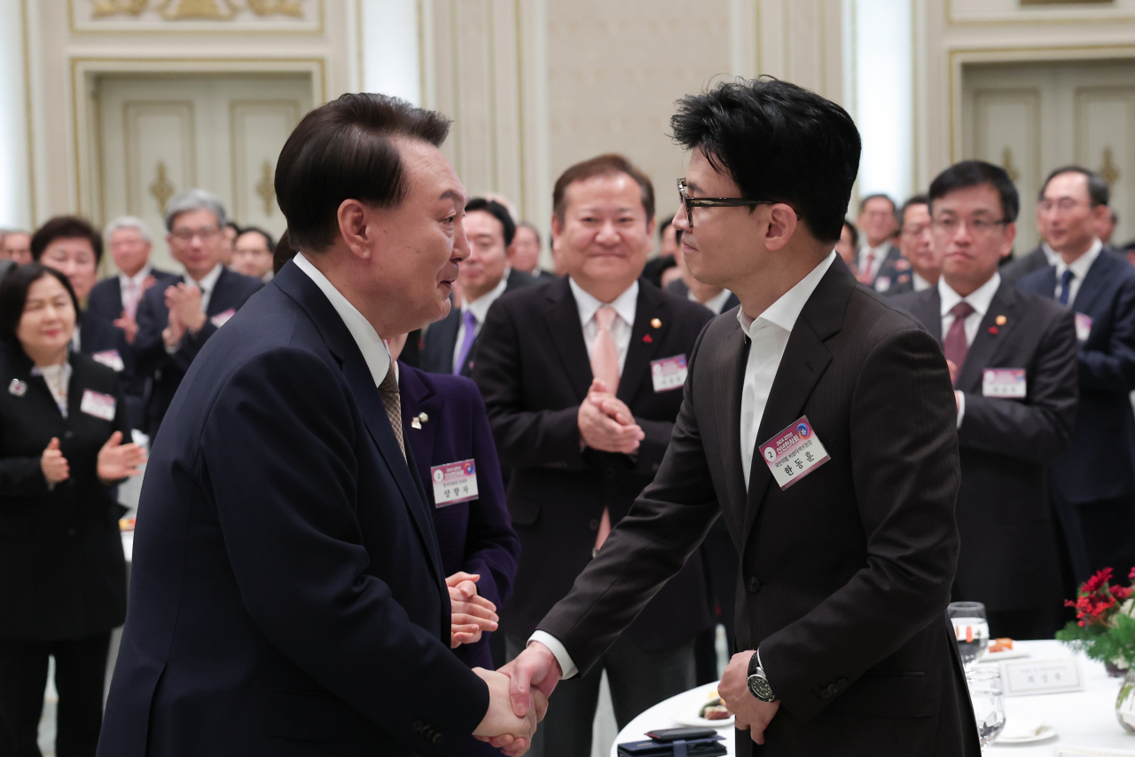President Yoon Suk Yeol (left) shakes hands with People Power Party interim leader Han Dong-hoon at a New Year's greeting session at Cheong Wa Dae on Wednesday. (Presidential office)