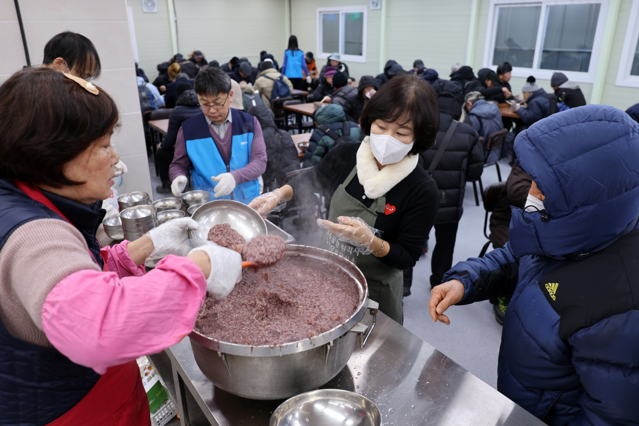Volunteers dish out complimentary lunches of red bean porridge for impoverished senior citizens at a park in Seoul on Dec. 22, 2023, the day of the winter solstice. People in Korea customarily eat the porridge on the winter solstice on the ancient belief that the red color of the beans provides positive energy to drive away evil spirits. (Yonhap)