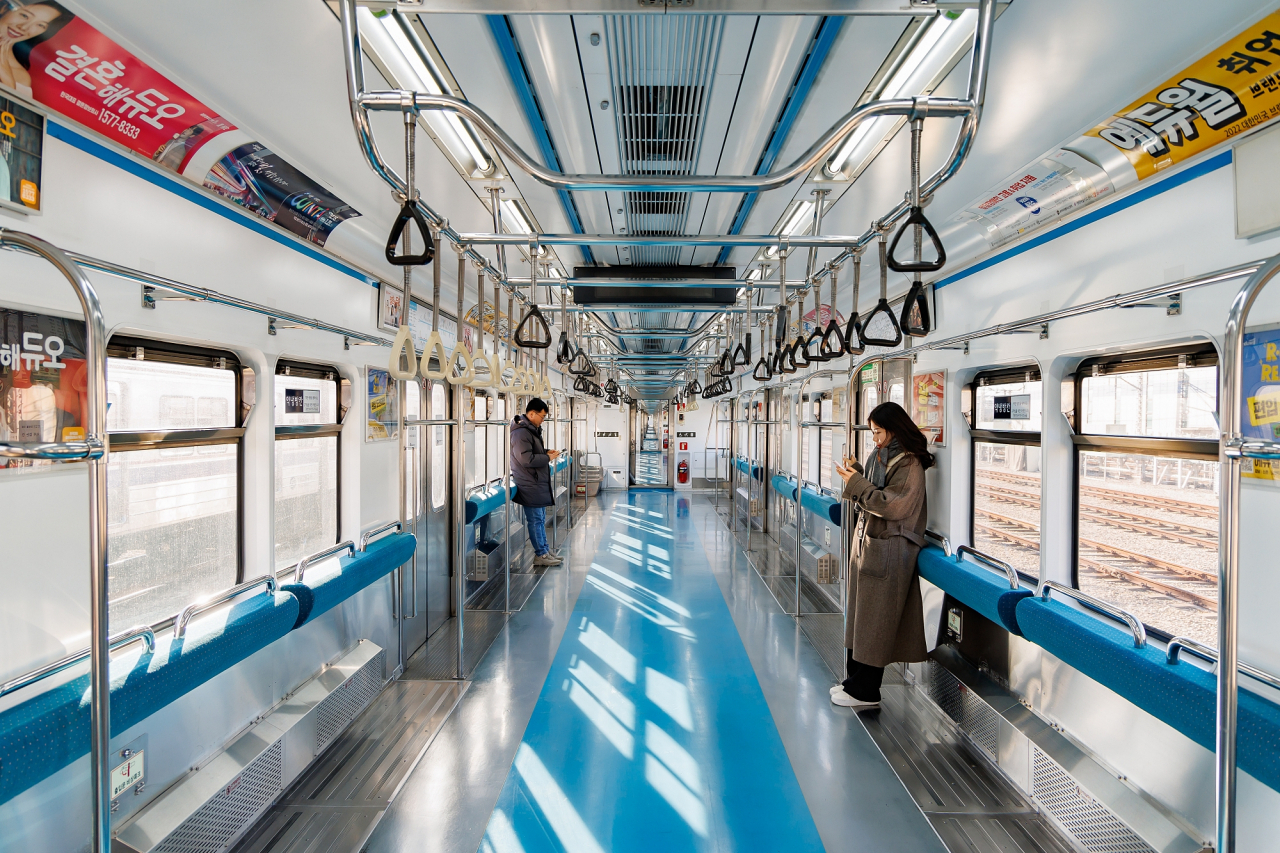 Two passengers on a Line No. 4 subway car, after seats have been removed (Seoul Metro)