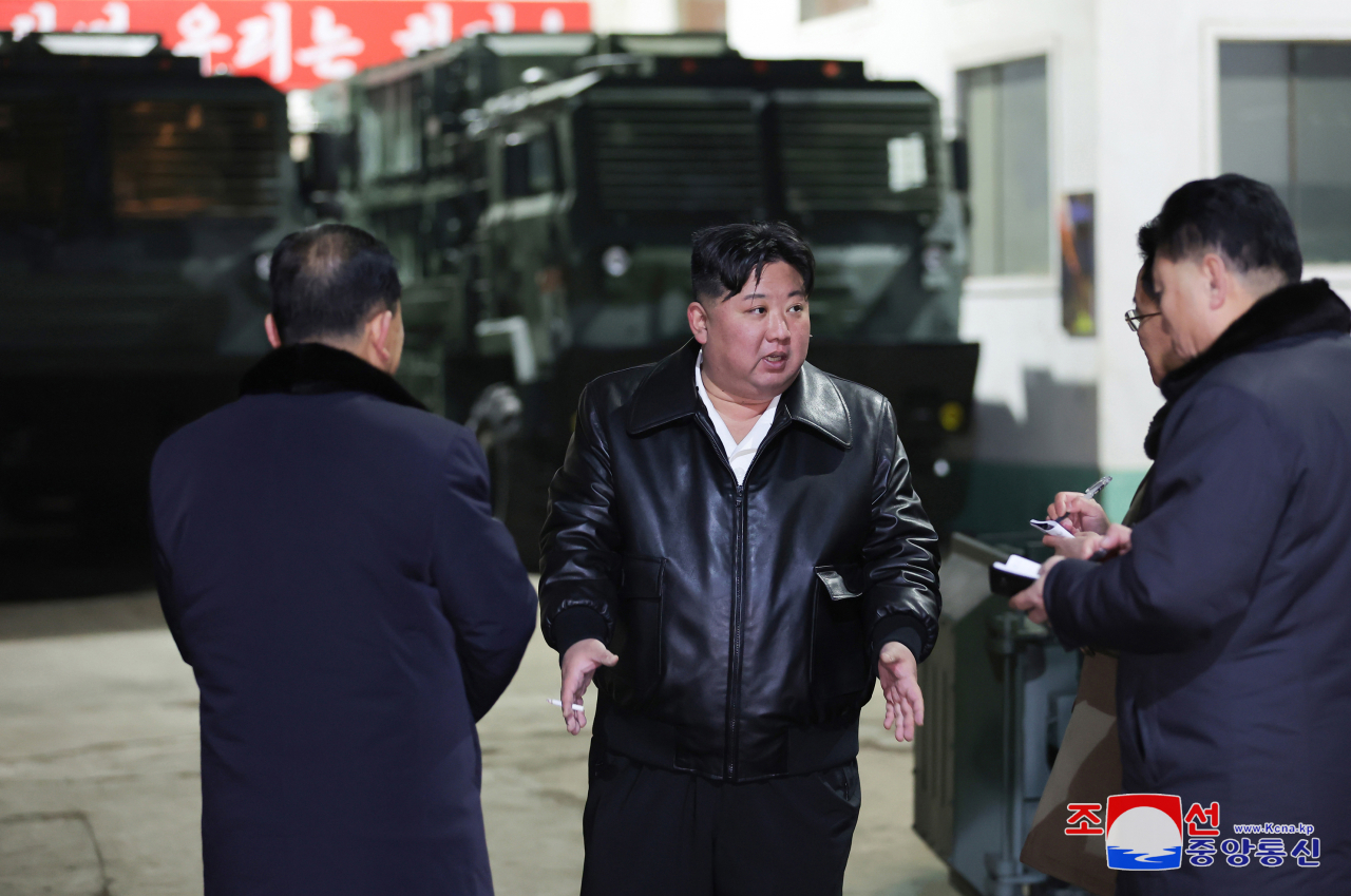 North Korean leader Kim Jong-un (center) talks to officials while inspecting a major munitions factory on Wednesday. (KCNA)