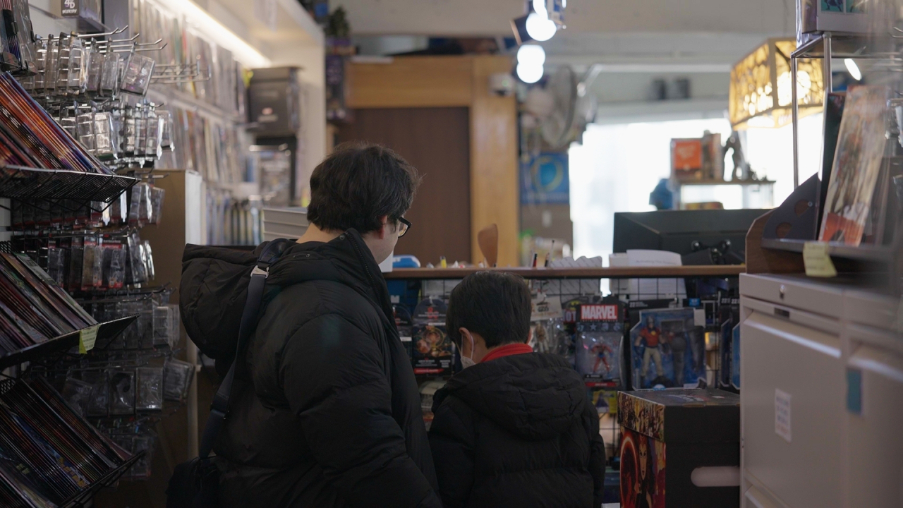 A father and son browse at Dice and Comics Cafe. (The Korea Herald)