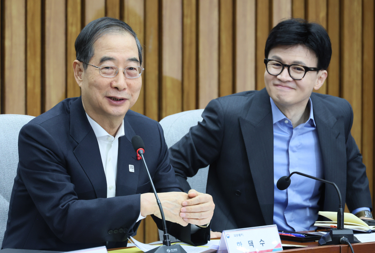 People Power Party Interim Leader Han Dong-hoon (right) smiles as Prime Minister Han Duck-soo speaks at a meeting of representatives of the government, the ruling party and the presidential office at the National Assembly in Seoul on Sunday. (Yonhap)