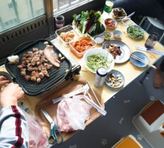 This photo of a person grilling pork belly on a portable gas burner inside an enclosed apartment balcony has touched off a heated online debate. (Courtesy of online community)