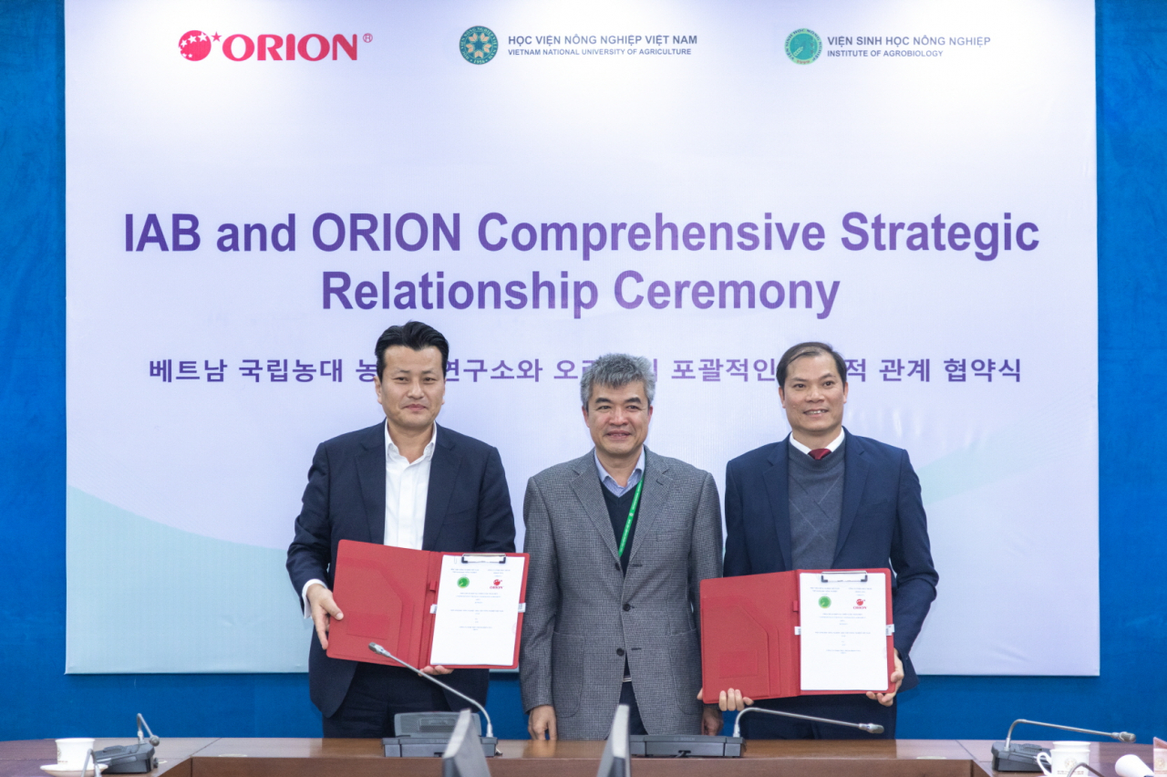 Orion Food Vina CEO Park Se-yeol (left) and Vietnam National University of Agriculture Vice President Pham Van Cuong (center) pose for a photo after a signing ceremony in Hanoi, Thursday. (Orion)