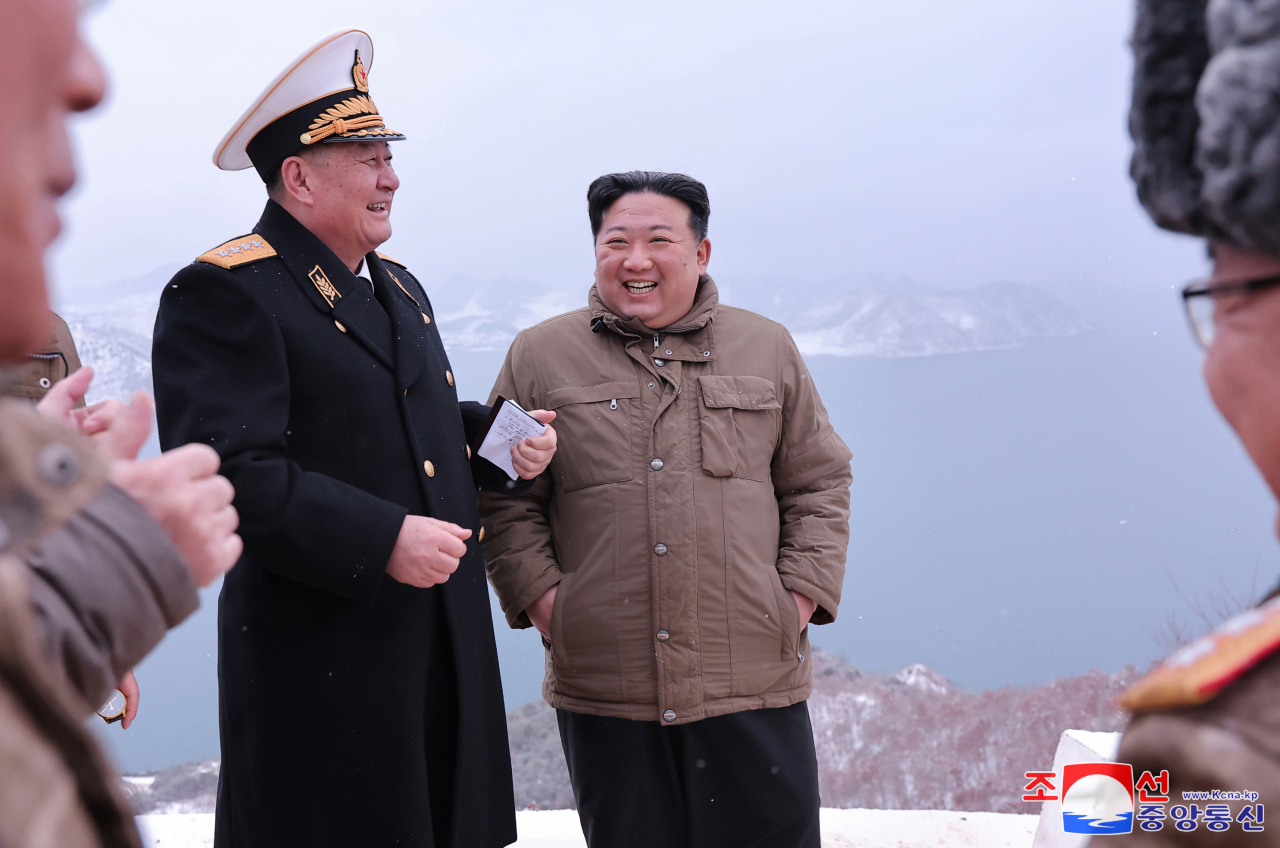 North Korean leader Kim Jong-un (center) talks with military officials as he watches a cruise missile being launched from a submarine on Sunday in this photo carried by the official Korean Central News Agency the next day. (KCNA)