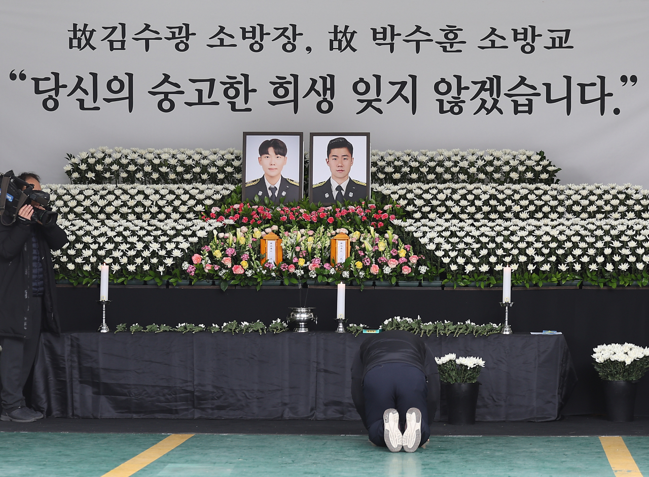 A visitor pays tribute to two firefighters, Kim Soo-kwang and Park Soo-hoon, who died after being trapped in a burning meat processing factory on Thursday, at a memorial altar installed at Mungyeong Fire Station in North Gyeongsang Province, Friday. (Yonhap)