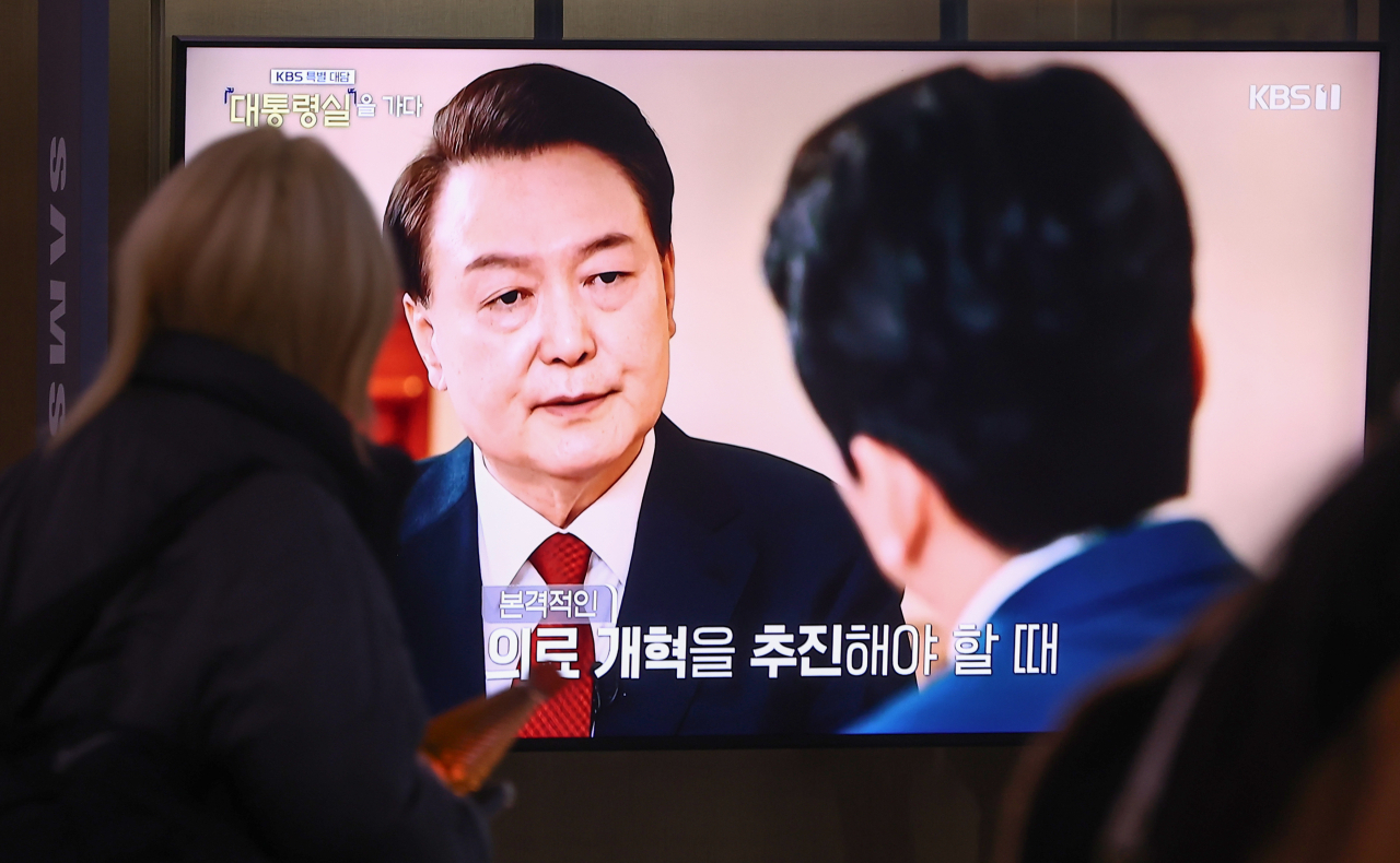 A pedestrian watches President Yoon Sul Yeol's televised interview with Korea Broadcasting System at Seoul Station on Wednesday. (Yonhap)