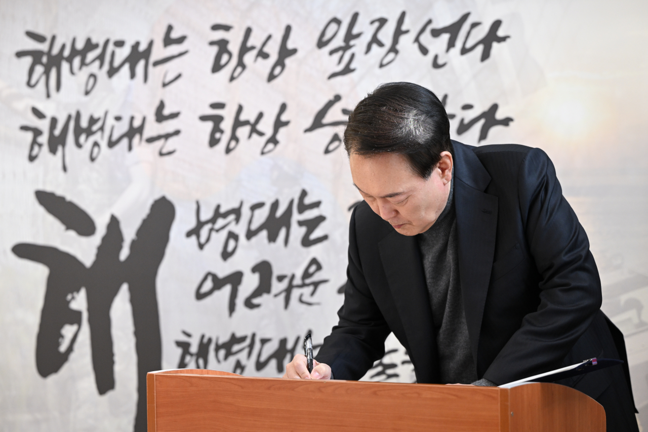 President Yoon Suk Yeol writes in a guestbook during a visit to the Marine Corps 2nd Division in Gimpo, just west of Seoul, on Saturday, on the Lunar New Year holiday, in this photo provided by the presidential office. (Yonhap)