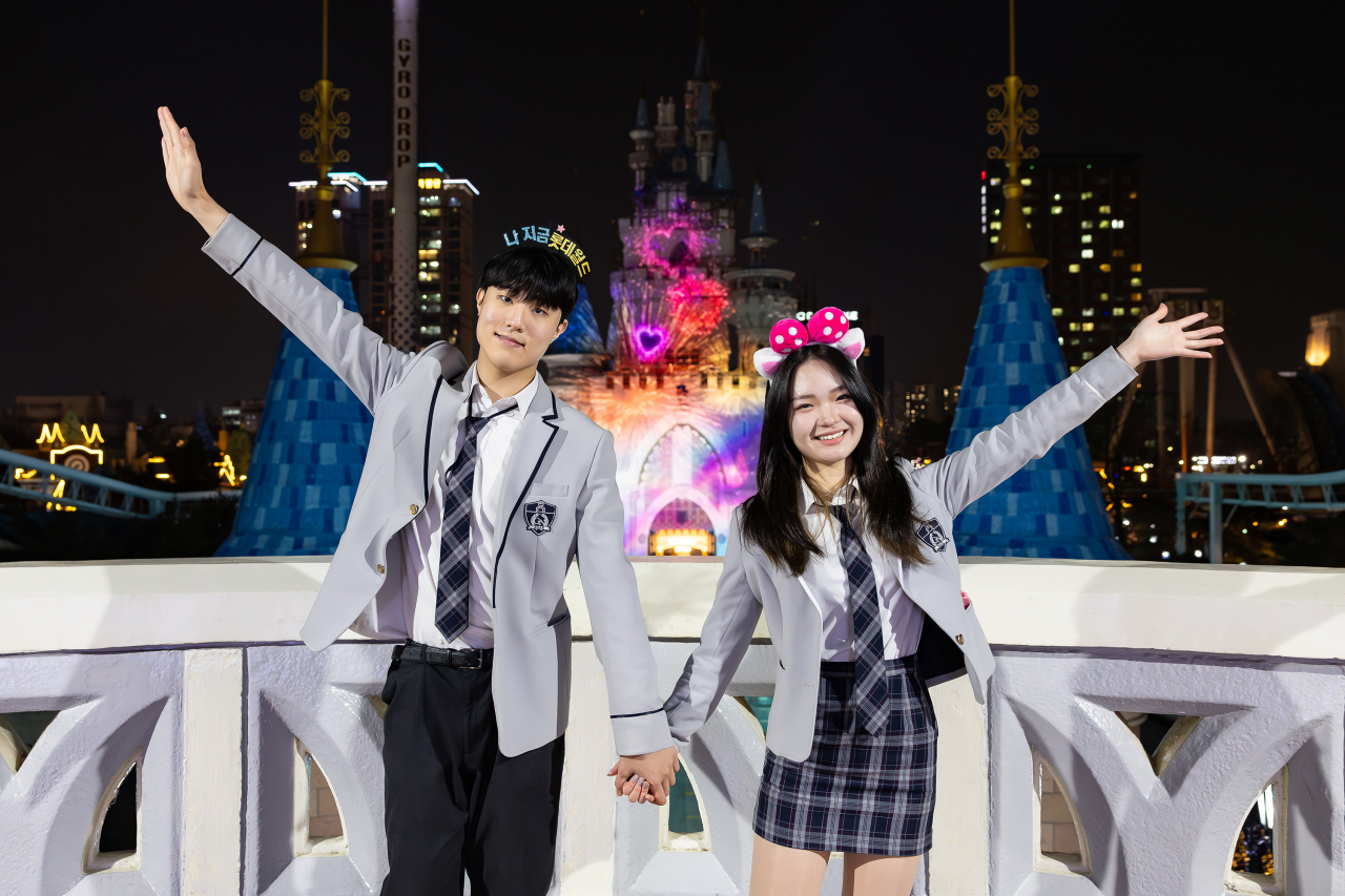 A couple poses for a photo with digital fireworks in the background at Lotte World Adventure. (Lotte World Adventure)