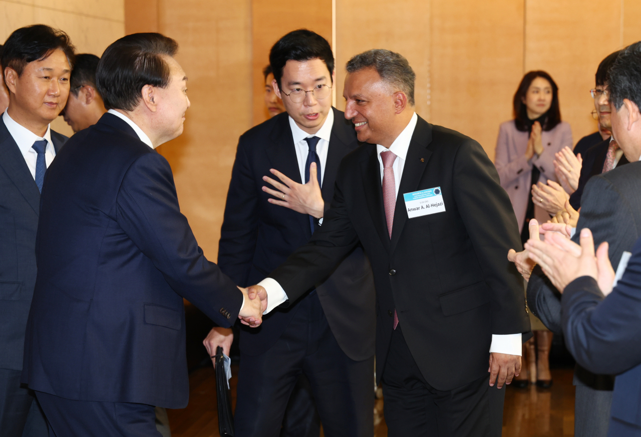 S-Oil CEO Anwar A. Al-Hejazi (right) shakes hands with President Yoon Suk Yeol at the presidential meeting with foreign-invested company representatives and heads of Seoul-based commerce chambers in Seoul on Wednesday. (Yonhap)