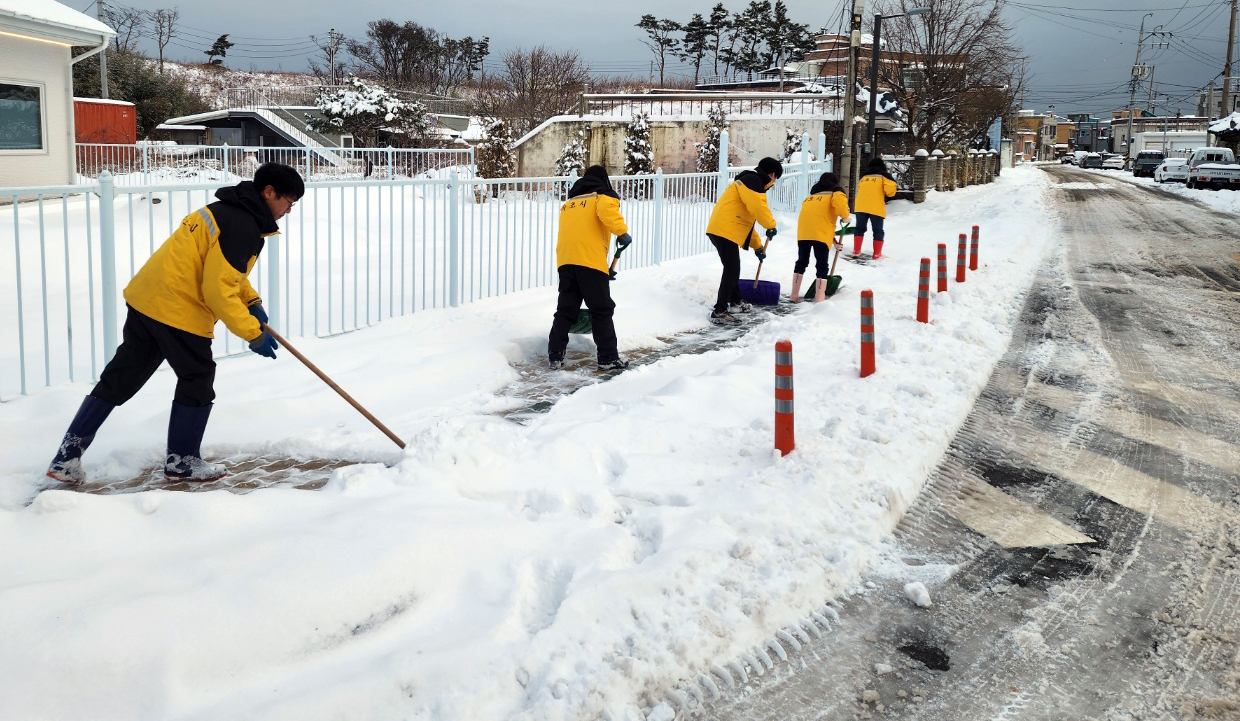 Government officials shovel snow on a street in Sokcho, Gangwon Province, Friday. (Yonhap)