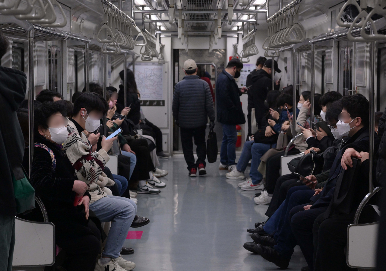 People stare at their phones as they ride the Seoul Metro on March 21, 2023. (Lee Sang-sub/The Korea Herald)