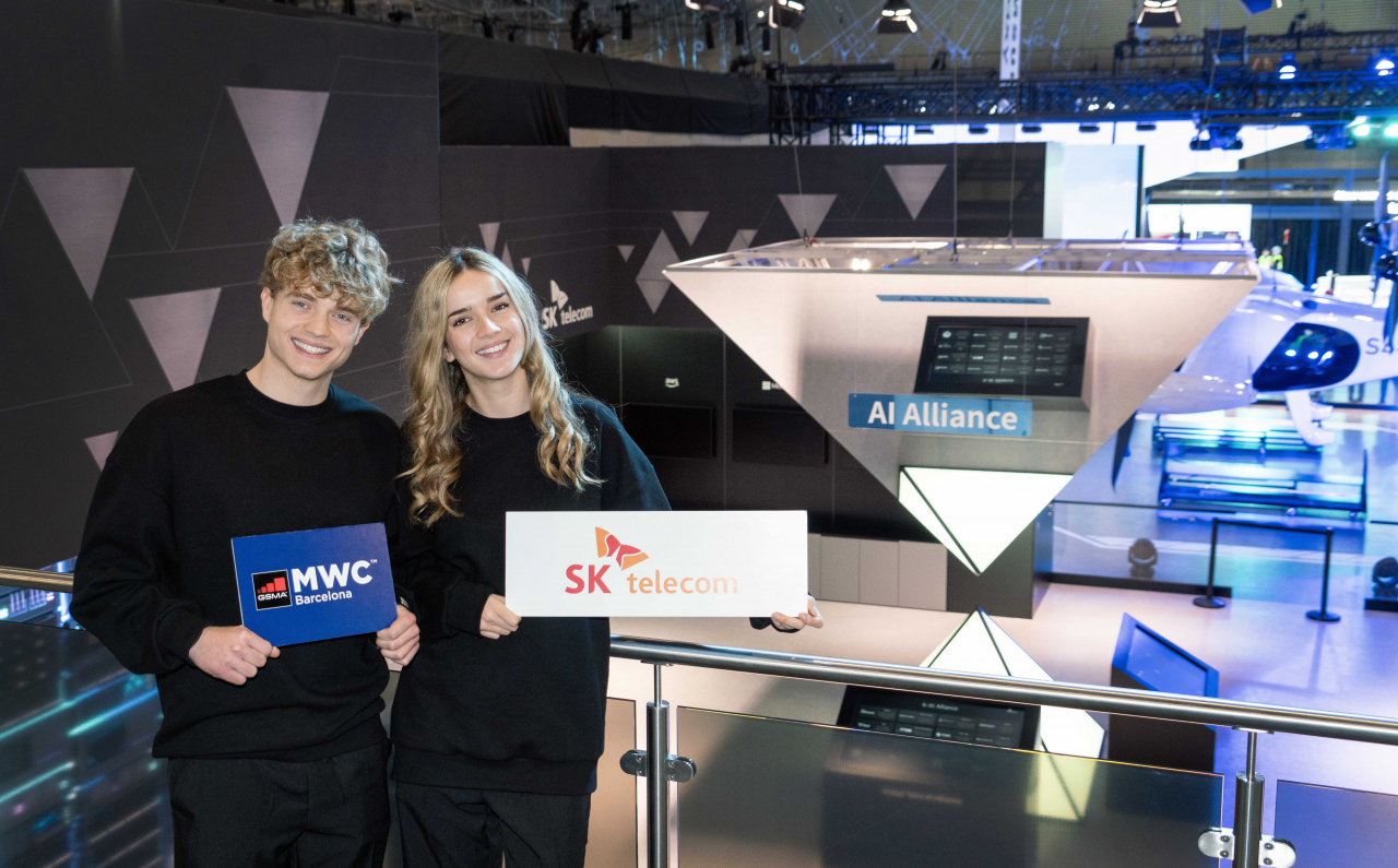 Models pose against the backdrop of the SK Telecom's Global Telco AI Alliance sculpture set up at the MWC 2024 in Barcelona, Spain. (SK Telecom)