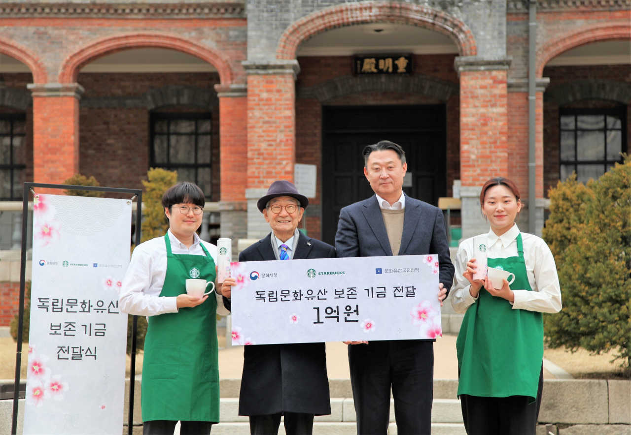 Starbucks Korea CEO Sohn Jeong-hyun (center right) and National Trust for Cultural Heritage Chairman Kim Jong-kyu (center left) pose for a photo during a donation ceremony at Deoksugung Palace in Seoul on Wednesday. (Starbucks Korea)