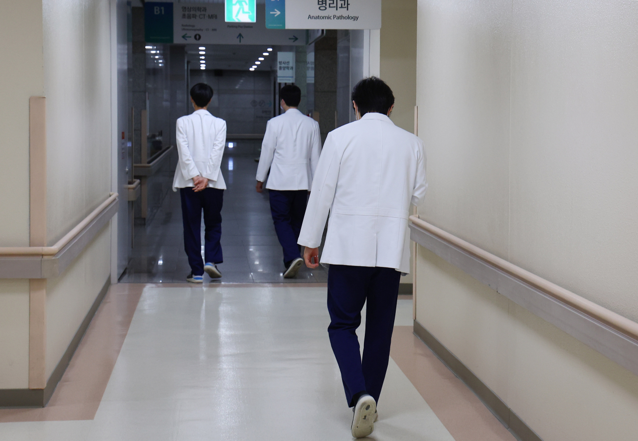 While the government has issued administrative orders such as suspension of licenses for strike doctors, doctors walk in a hospital in Incheon. (Yonhap)
