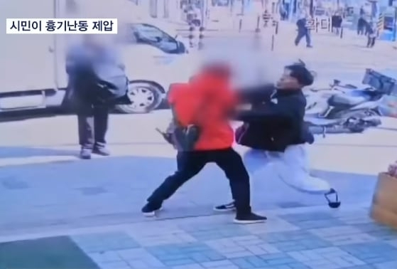 This screenshot from a local news report shows Jo Yu-chan (right) struggling with the suspect to take his knife away in Suyu-dong, northern Seoul on Friday. (MBN)