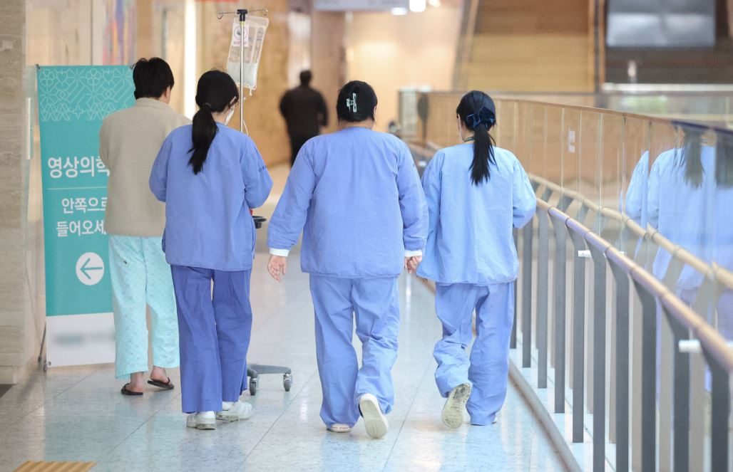 Medical workers and a patient walk in a hallway at a general hospital in Seoul on Sunday. (Yonhap)