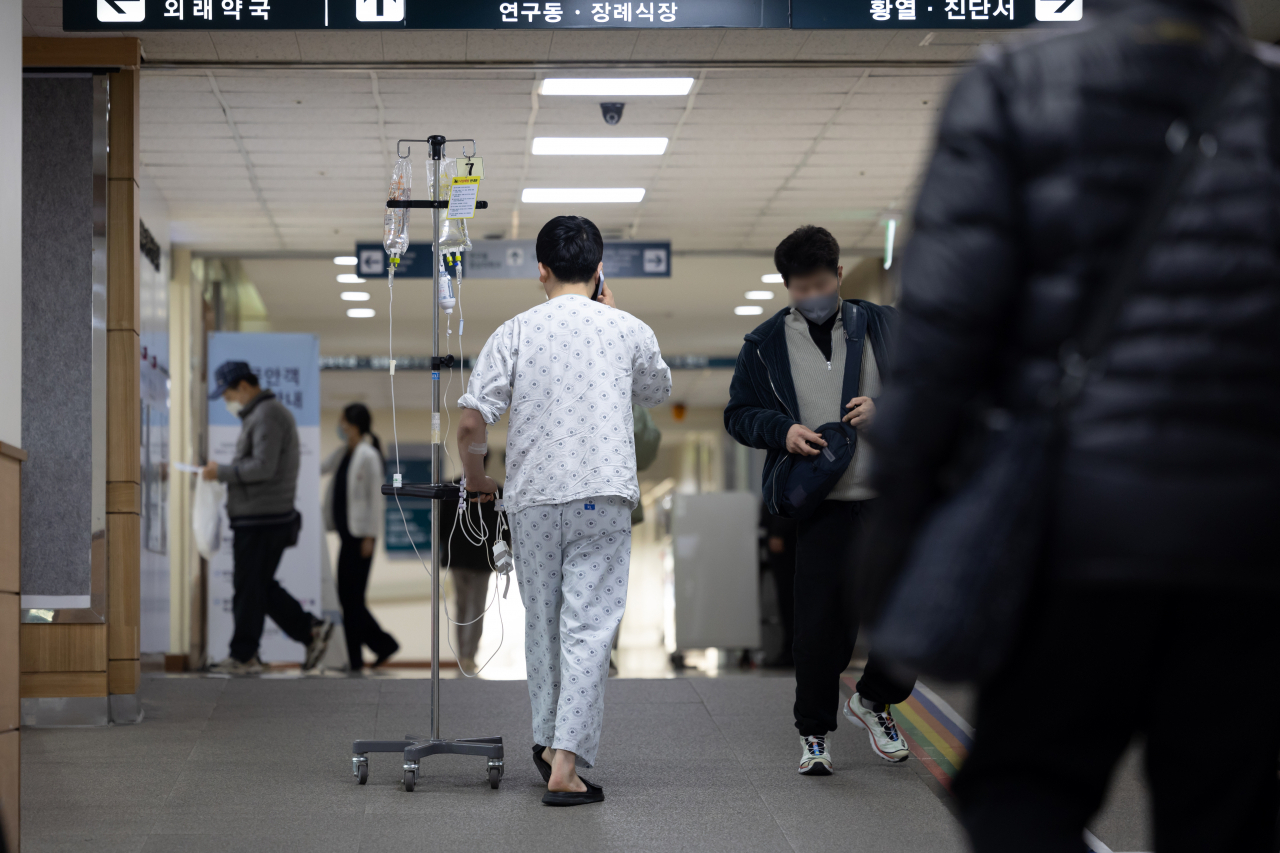 A patient with an IV bag walks down a hallway at a hospital in Seoul, Wednesday. (Yonhap)