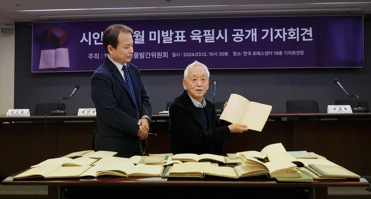 Park Dong-gyu (right) holds up one of the notebooks of his father, the late poet Park Mok-wol, during a press conference in Seoul on Tuesday. (Yonhap)