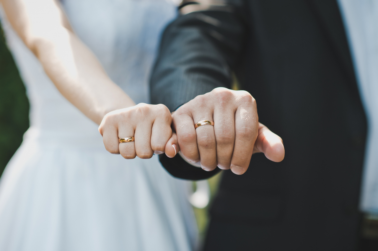 A bride and groom with wedding rings on their fingers (123rf)