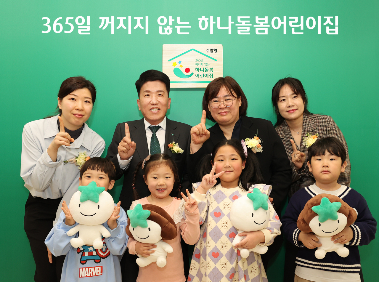 Hana Financial Group Chairman Ham Young-joo (second from left, back row) poses with parents and children to celebrate the initiation of the 365 Day Child Care project at a child care center in Nowon-gu, Seoul, Tuesday. (Hana Financial Group)