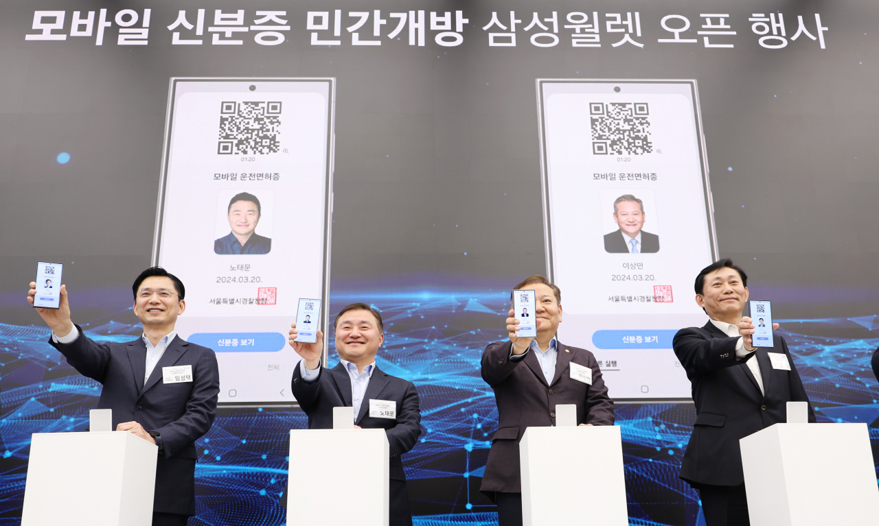 From left: Samsung Electronics Vice President Lim Seong-taek, Samsung Electronics President Roh Tae-moon, Interior Minister Lee Sang-min and Presidential Committee on the Digital Platform Government Chair Go Jin show their mobile identification cards on Samsung Wallet during an open event, Wednesday. (Yonhap)