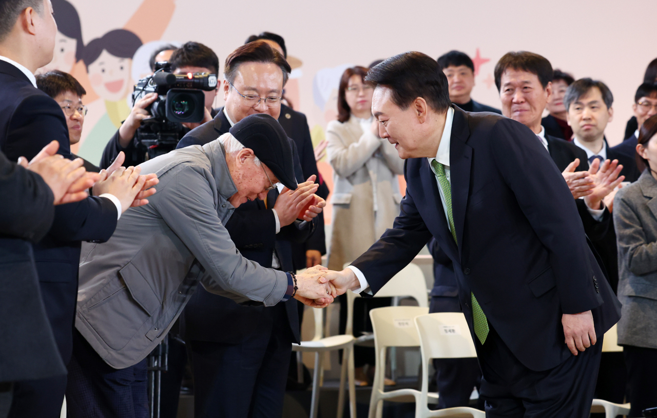 President Yoon Suk Yeol (right) shakes hands with a senior citizen who attended a policy debate held at the headquarters of the Health Insurance Review and Assessment Service in Wonju, Gangwon Province, Thursday. (Pool photo via Yonhap)