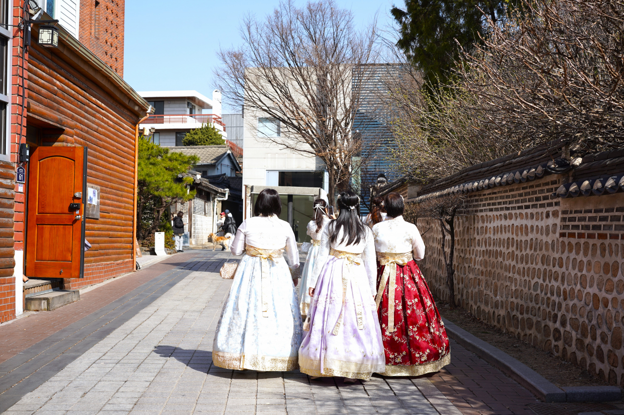 Hanbok-clad visitors explore Yunboseon-gil, in Seoul, Monday. (Lee Si-jin/The Korea Herald)