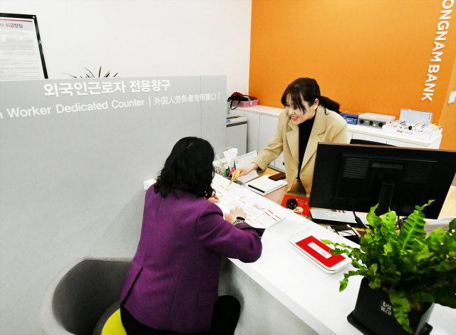 An employee serves a foreign customer at BNK Kyongnam Bank's branch located in Ulsan. (BNK Kyongnam Bank')