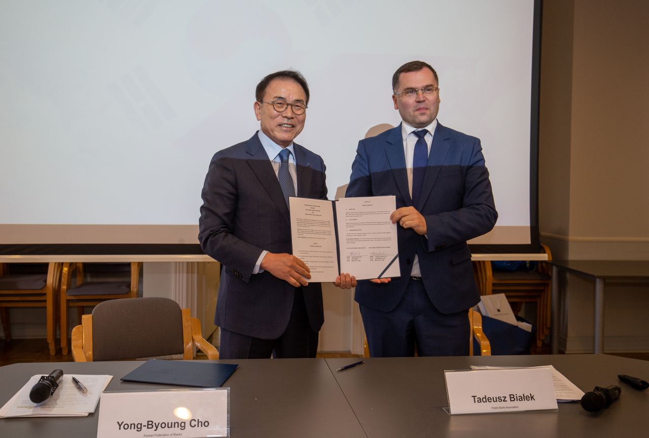 Cho Yong-byoung (left), the chair of Korea Federation of Banks, poses for a picture with Tadeusz Białek, the president of Polish Bank Association, after signing a memorandum of understanding on Monday at the Banker's Club in Warsaw, Poland. (Korea Federation of Banks)