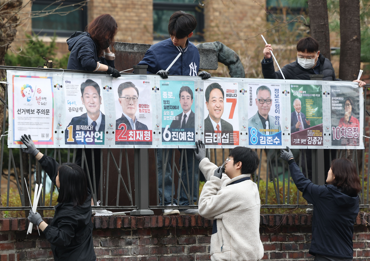 Election officials affix a poster showing candidates to a wall in the Jongno constituency in Seoul on Thursday, as the official campaigning period for the April 10 general election started. (Yonhap)