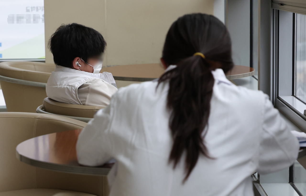 A medical personnel and a child patient sit at a resting lounge in a hospital in Seoul on Friday. (Yonhap)