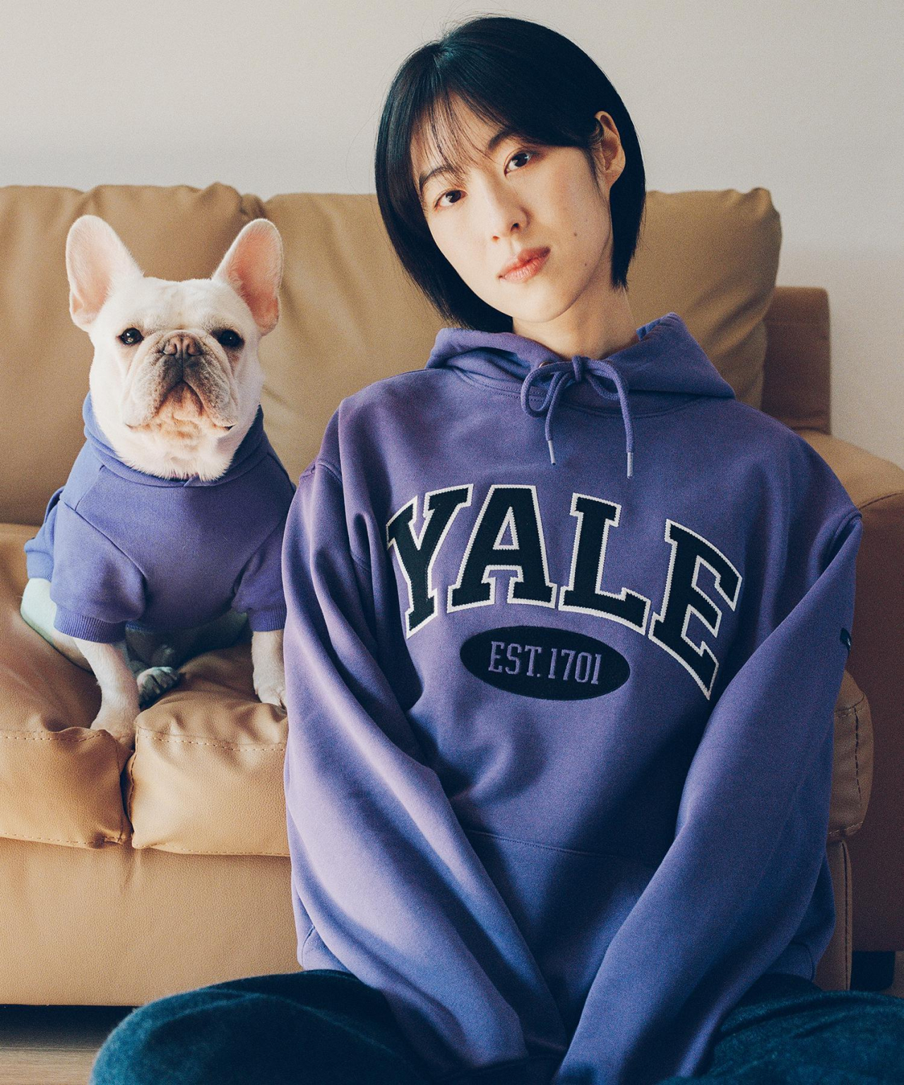 A model wearing Yale's hooded sweatshirt poses for a photo with a dog. (PHYPS Department)