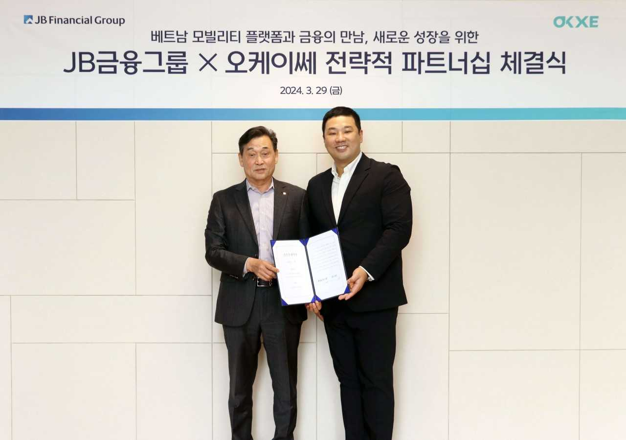 JB Financial Group Chairman Kim Ki-hong (left) and OKXE CEO Kim Woo-seok pose for a photo at a signing ceremony held in Seoul on Friday. (JB Financial Group)