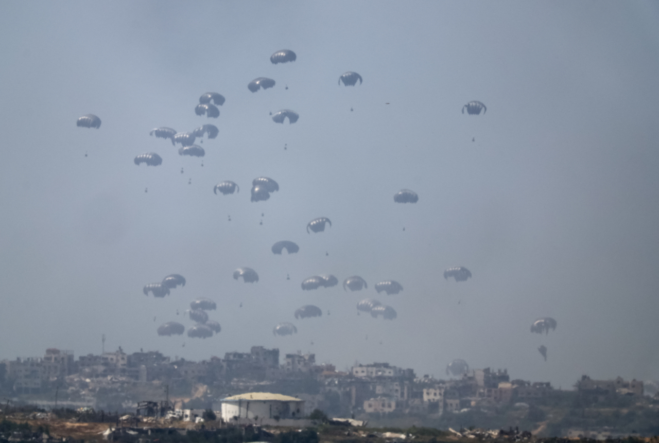 Humanitarian aid falls through the sky towards the Gaza Strip after being dropped from an aircraft, amid the ongoing conflict between Israel and the Palestinian Islamist group Hamas, as seen from Israel, Tuesday. (Reuters-Yonhap)