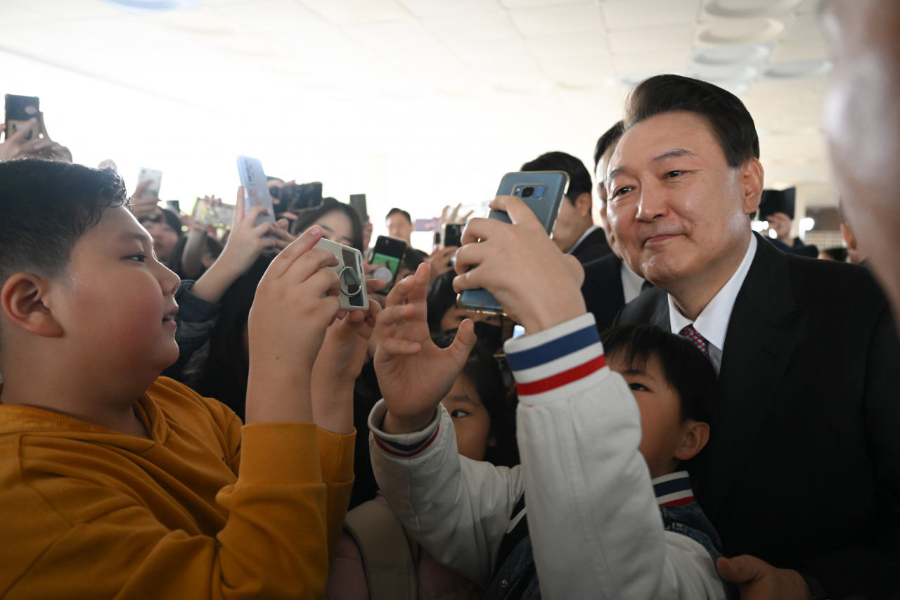 President Yoon Suk Yeol takes pictures with students after teaching them as a one-day teacher for the state's childcare program at Ain Elementary School in Hwasung, Gyeonggi Province on Friday. (Yonhap)