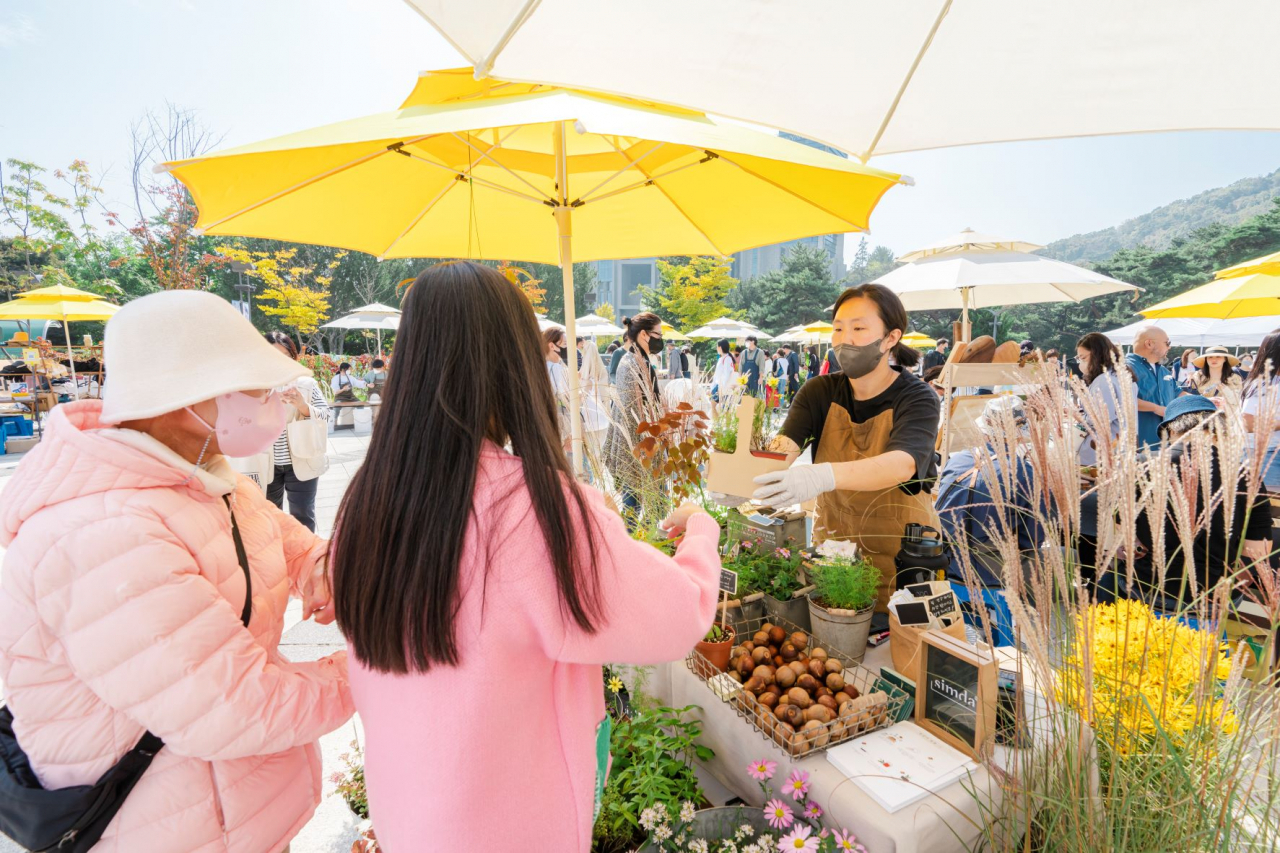 Visitors make a purchase at “Art in Marche” in front of the National Theater of Korea in 2023. (National Theater of Korea)